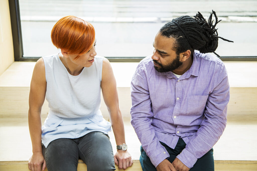 A couple sitting talking to each other and apologizing to the other for their recent words and actions